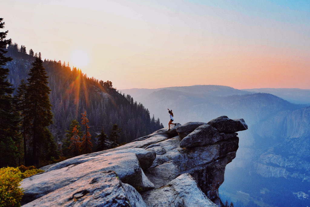 A picture of a woman at the edge of a fantastic view of a forest