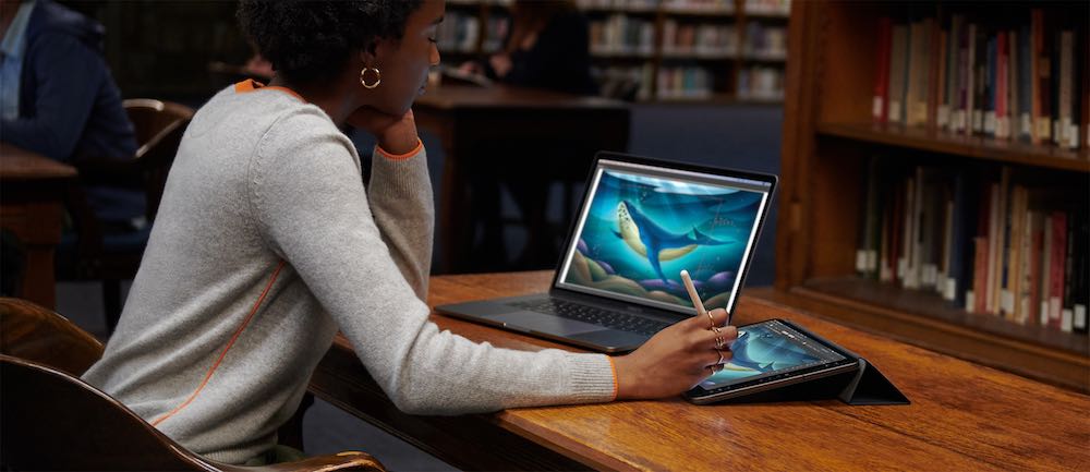 A woman using iPad and Mac in Sidecar mode